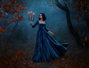 Fantasy woman queen runs in dark forest, hands hold vintage burning candlestick three candles. Blue...