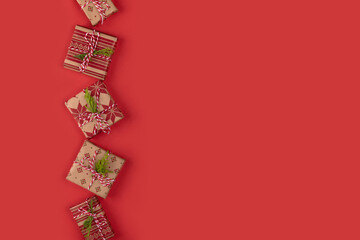 Top view of Christmas gift boxes on red background. New Year flat lay with presents wrapped with craft paper. Copy space.