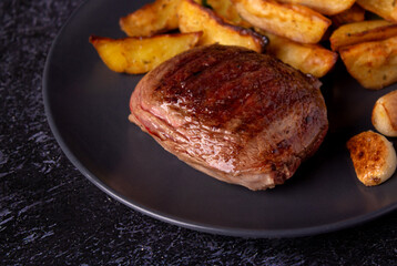Photo of grilled marbled beef steak with potatoes and garlic on black