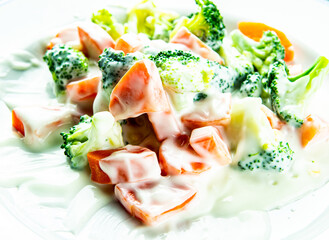 Broccoli and carrot with white sauce in plate,  close up in studio Chiangmai Thailand.