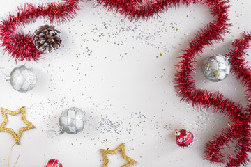 Flat lay xmas composition with empty space. Red tinsel, golden stars, silver Christmas balls and glitter with bokeh lights. New Year backplate for your design or postcard. Happy holidays concept