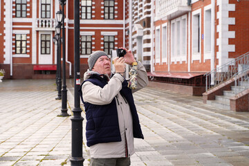 elderly man photographs sights in the city. Yoshkar-Ola, Russia - 467152854