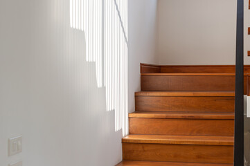 light and shadow on wooden stair steps with black steel handrail. house interior concept.