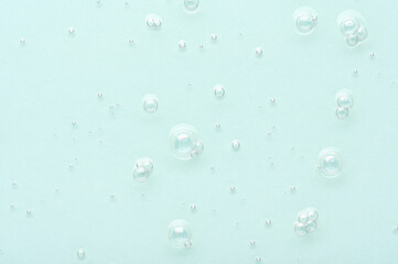 Texture of skincare cosmetic emulsion with small air bubbles on turquoise background upper view....