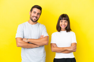Obraz premium Young couple isolated on yellow background keeping the arms crossed in frontal position
