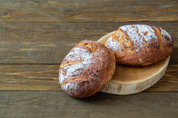 two fresh white breads lie together on a cut oak tree on a wooden background rustic
