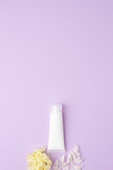 White tube of cosmetic cream with flowers on rose background. Flat lay, copy space