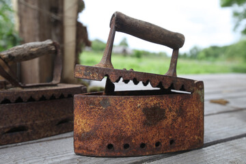 Photo of an old rusty iron that stands on a table on the street in the village
