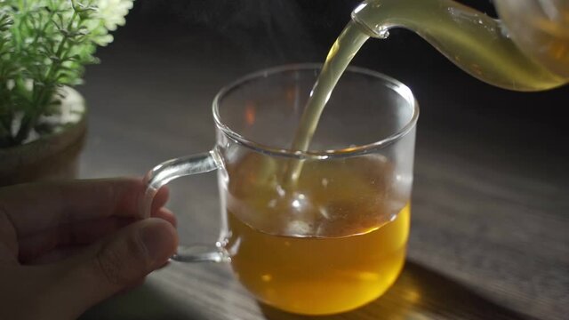 温かいお茶をコップに注ぎ、湯気が出ている