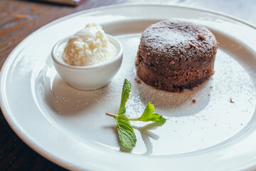 Restaurant dessert on the table. White plate, ice cream and chocolate sponge cake with powdered...