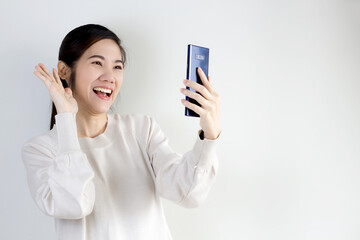 Asian beautiful woman hold smartphone and raise hand video call to say hello and talk to family with a happiness and smiling.