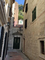 Fototapeta na wymiar La ville ancienne de Kotor, à Monténégro, ruelle ou petite place historique et dans de la pierre, complétement dans l'ombre et tout fermé, vide et personne, ambiance tranquille