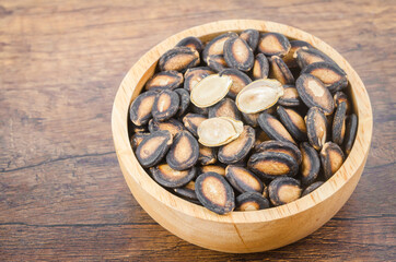 Black dry watermelon seeds in wooden bowl.