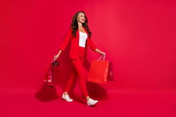 Fototapeta na wymiar Full size photo of funky pretty brunette lady go do shopping wear suit shoes isolated on red color background