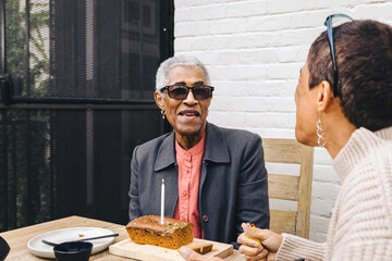 Black woman smiling with her birthday cake while sitting in her backyard