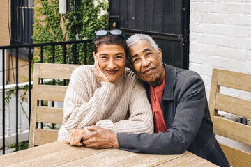 An elderly black woman and her adult daughter embrace for a portrait in the backyard