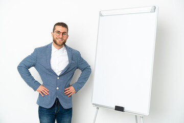 Young business woman giving a presentation on white board isolated on white background posing with arms at hip and smiling