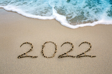 New Year 2022 written at the caribbean sand beach with sea wave .