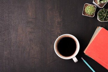 Coffee cup with cactus and book on the wooden background with copy space, top view