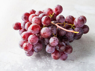 Bunch of fresh ripe red grapes isolated on white concrete background.