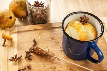 Blue enamel metal mug with anise stars, cane sugar caramel and fruits on bamboo wood