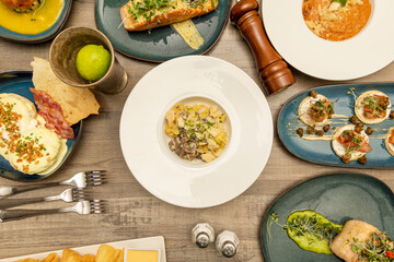 Set of international dishes, risotto with parmesan and mushrooms, eggs Benedict, blisins, fried yucca, grilled salmon, hake in sauce