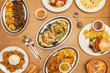 selection of international dishes, gnocchi with cheese and nuts, grilled beef, hamburger with potatoes, breaded chicken strips, prawn cocktail, forks