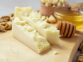 slices of hard cheese on a wooden board with nuts and honey the best combination