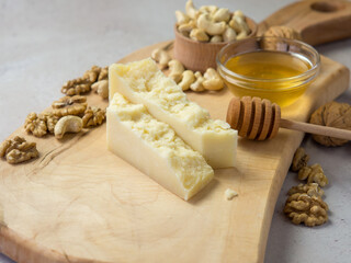 slices of hard cheese on a wooden board with nuts and honey the best combination