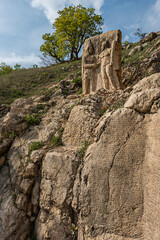 stone sculptures of Greek deities with stone wall full of sculpted scriptures on the foothills of...