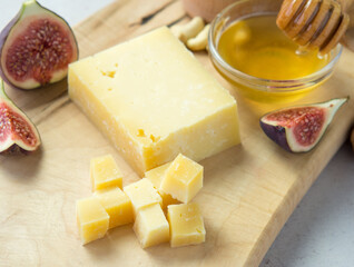 Pieces of aged cheese, nuts, figs and honey on a cutting board,