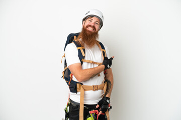 Young rock- climber reddish caucasian man isolated on white background pointing back
