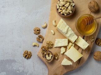 farm cheese served with honey and nuts on a light texture background. Copy space