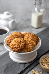 Delicious homemade oat cookies with a cup of coffee, healthy sweet snack, bright background.
