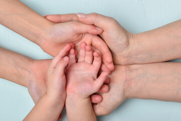 Fototapeta premium The open palms of the mother in which the open palms of the children lie, there is an empty space. The banner of family and unity.