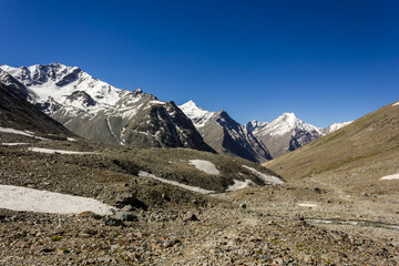 Fototapeta premium A view of the snow capped Himalayan mountain range on the trekking trail between Darcha and Padum in the Zanskar valley.