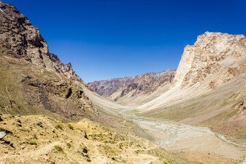 Barren mountains of the cold desert wilderness of the Zanskar valley under a blue sky on a sunny day in the Ladakh region in North India.