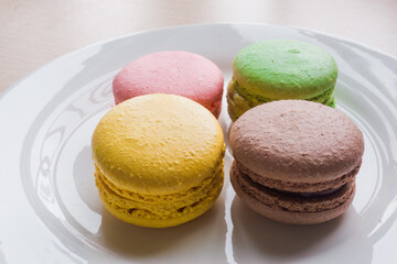 Close up colorful macarons cakes. Macaroons isolated on a white plate. 
A french sweet delicacy.