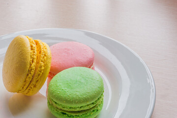 Close up colorful macarons cakes. Macaroons isolated on a white plate. 
A french sweet delicacy.