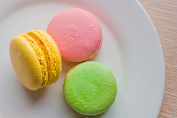 Close up colorful macarons cakes. Macaroons isolated on a white plate. 
A french sweet delicacy.