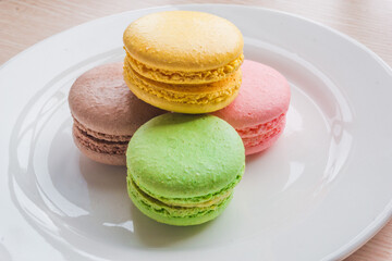 Close up colorful macarons cakes. Macaroons isolated on a white plate. 
A french sweet delicacy.