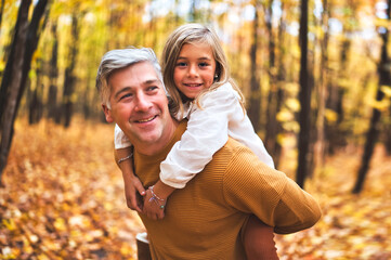 Father and daughter having fun in the autumn colorful forest