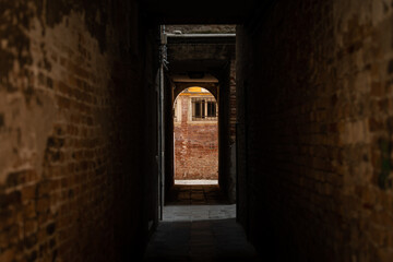 Fototapeta na wymiar Dark narrow street in Venice brick walls