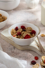 Corn flakes with strawberry and blueberry in black bowls over dark background, top view.