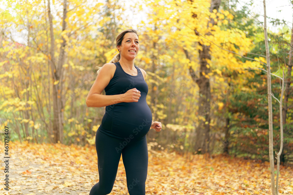 Wall mural fit pregnant woman standing outside on a sunny day