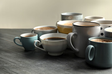 Many cups of different coffees on slate table