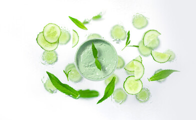 Composition with organic moisturizer cream jar with eco plant leaves, cucumber on white background. Flat lay, top view, copy space. Natural organic products, beauty and SPA concept