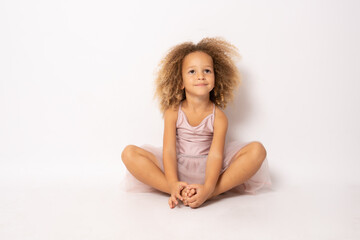 Obraz na płótnie Canvas Beautiful little ballerina sitting on floor isolated over white background