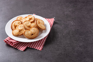 Palmier puff pastry in plate on black background. Copy space