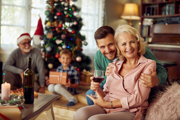 Happy senior woman and her adult son enjoy on Christmas day with their family at home.